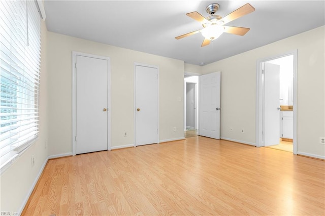 unfurnished bedroom with connected bathroom, two closets, light hardwood / wood-style flooring, and ceiling fan