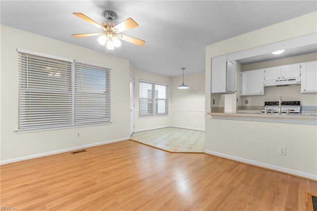 kitchen featuring ceiling fan, sink, light hardwood / wood-style flooring, white cabinetry, and hanging light fixtures