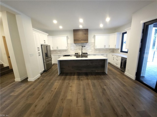 kitchen with white cabinetry, dark hardwood / wood-style flooring, backsplash, a kitchen island with sink, and high end fridge