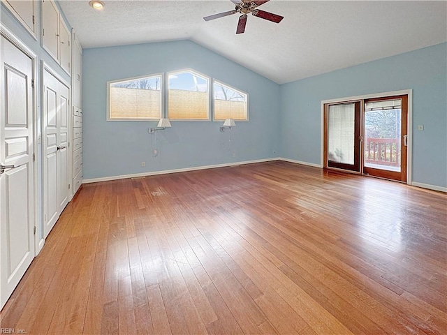 unfurnished bedroom featuring ceiling fan, light wood-type flooring, lofted ceiling, and a textured ceiling