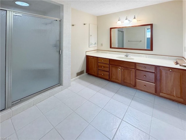 bathroom featuring vanity, a textured ceiling, tile patterned floors, and a shower with door