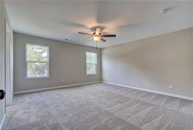 unfurnished room with plenty of natural light, ceiling fan, and light colored carpet