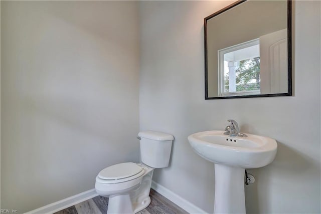 bathroom with toilet, wood-type flooring, and sink