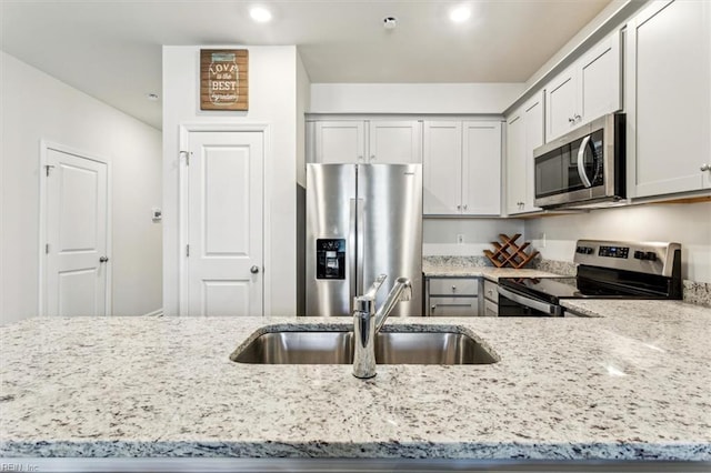 kitchen featuring appliances with stainless steel finishes, light stone counters, and sink