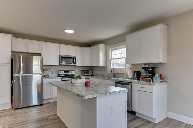 kitchen featuring a center island, stainless steel appliances, white cabinetry, and sink