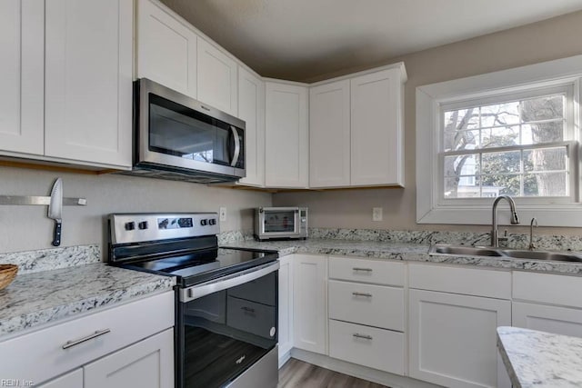 kitchen featuring sink, light hardwood / wood-style flooring, light stone counters, white cabinetry, and stainless steel appliances