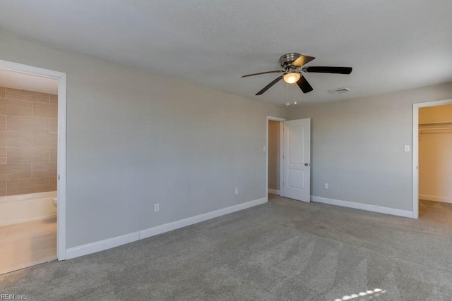 unfurnished bedroom with light carpet, ensuite bath, ceiling fan, a spacious closet, and a closet