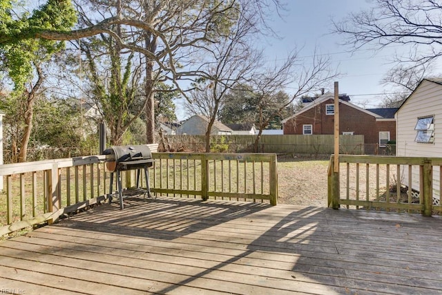 wooden terrace featuring a yard and a grill