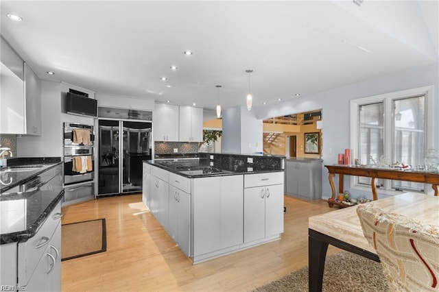 kitchen featuring a spacious island, white cabinetry, hanging light fixtures, and built in fridge