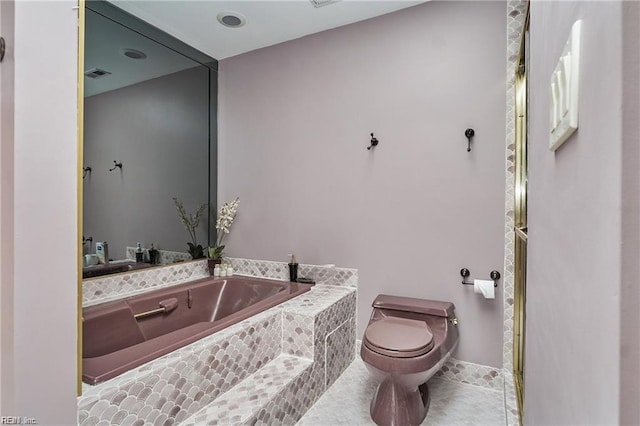 bathroom featuring tile patterned floors, toilet, and tiled tub