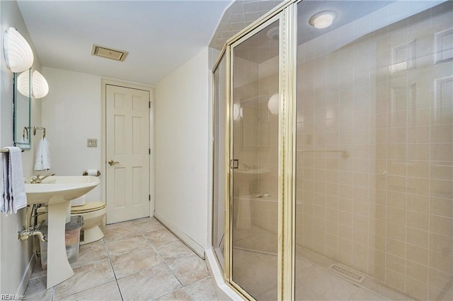 bathroom featuring tile patterned flooring, toilet, and an enclosed shower