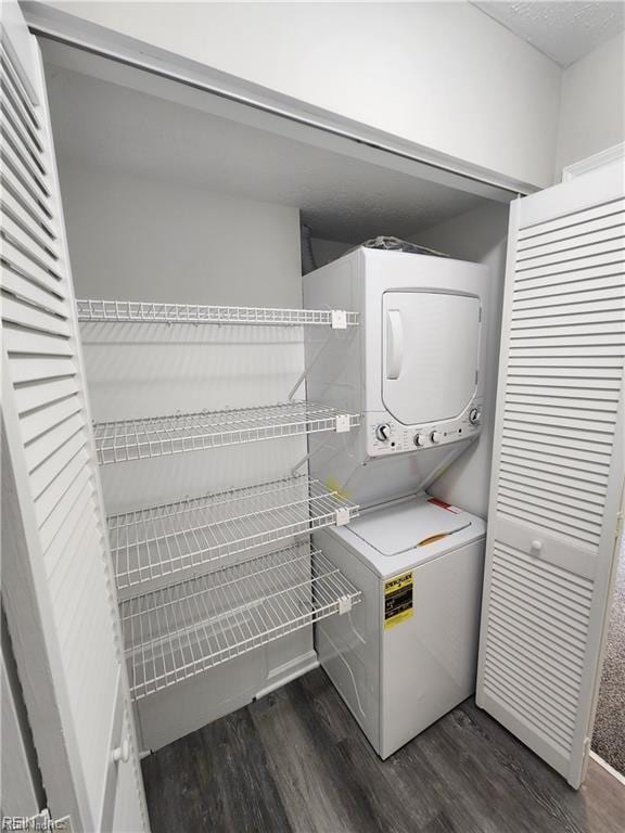 laundry room with dark hardwood / wood-style floors and stacked washer and clothes dryer