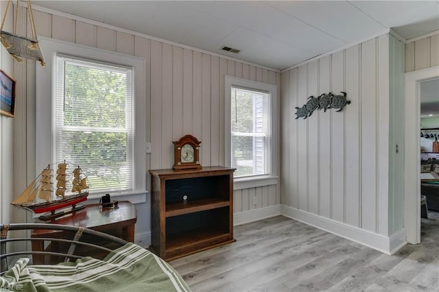 living area with ornamental molding and light hardwood / wood-style flooring