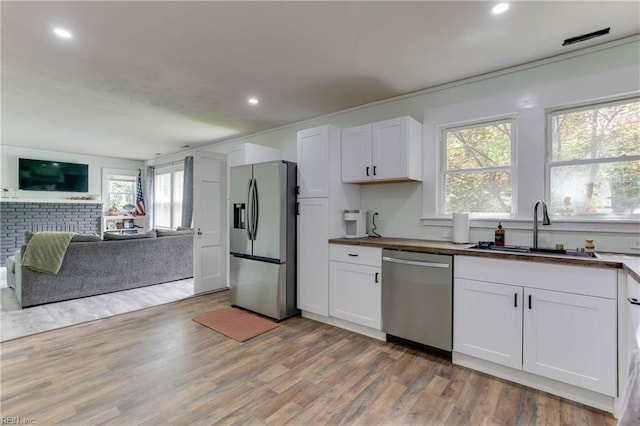 kitchen featuring wooden counters, stainless steel appliances, white cabinets, and sink