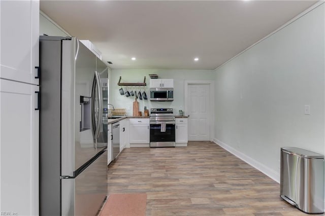 kitchen featuring light wood-type flooring, white cabinetry, sink, and appliances with stainless steel finishes