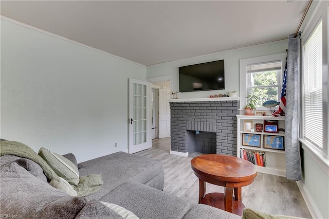 living room with french doors, light hardwood / wood-style floors, and a brick fireplace