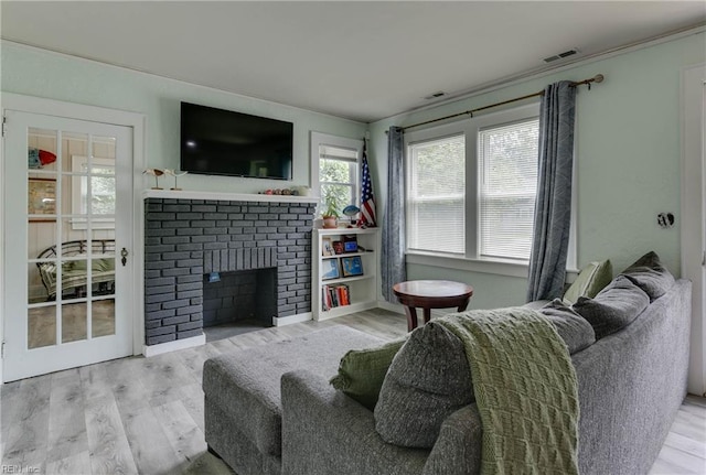 living room with light hardwood / wood-style flooring, plenty of natural light, and a brick fireplace