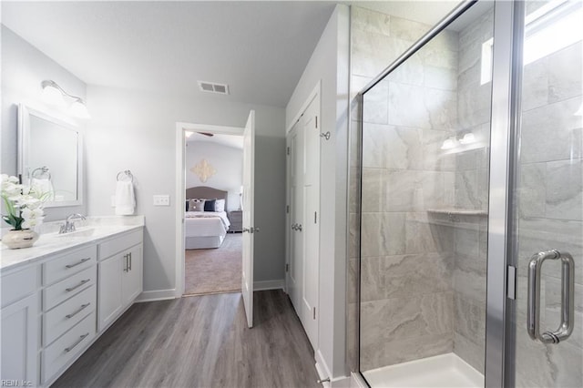 bathroom with hardwood / wood-style floors, vanity, and a shower with shower door