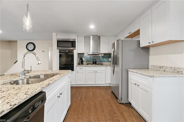 kitchen featuring wall chimney exhaust hood, stainless steel appliances, sink, white cabinetry, and hanging light fixtures