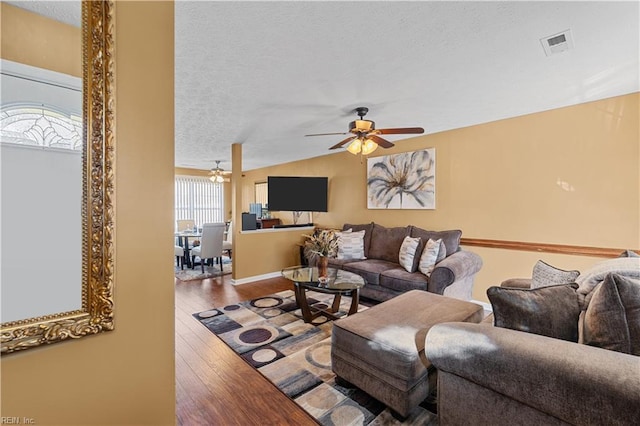 living room with a textured ceiling, ceiling fan, hardwood / wood-style floors, and vaulted ceiling