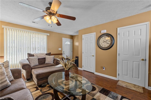 living room featuring ceiling fan, a textured ceiling, and dark wood-type flooring