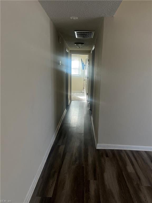 corridor featuring a textured ceiling and dark wood-type flooring