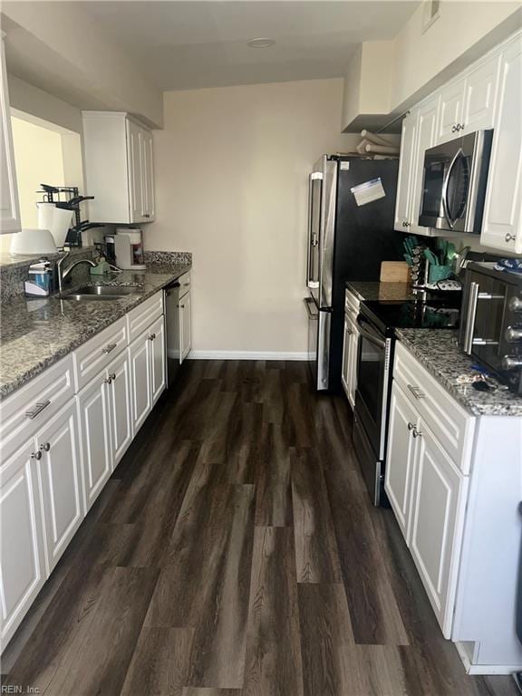 kitchen with stainless steel appliances, stone counters, dark hardwood / wood-style floors, white cabinets, and sink