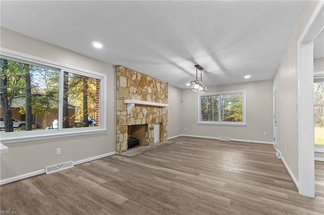 unfurnished living room featuring a stone fireplace and wood-type flooring