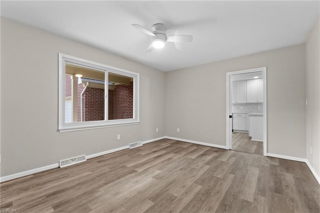 unfurnished bedroom featuring ceiling fan, light wood-type flooring, and ensuite bath