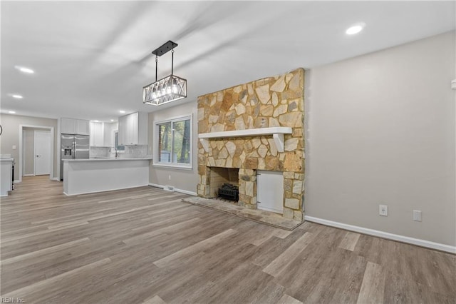 unfurnished living room with light hardwood / wood-style flooring, a stone fireplace, and sink