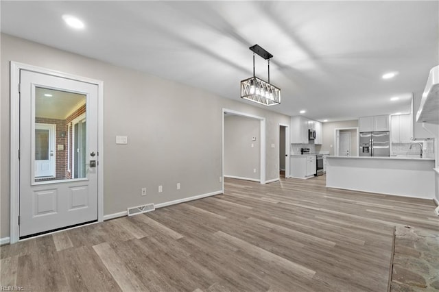 unfurnished living room featuring light hardwood / wood-style flooring and sink