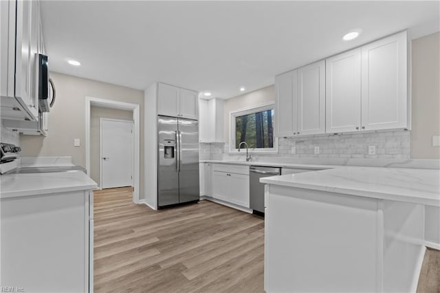 kitchen featuring light stone countertops, light hardwood / wood-style flooring, white cabinets, and appliances with stainless steel finishes