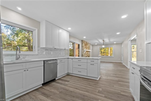 kitchen with white cabinetry, sink, kitchen peninsula, decorative backsplash, and appliances with stainless steel finishes