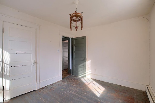 unfurnished bedroom with dark hardwood / wood-style flooring and baseboard heating