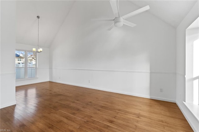 spare room with hardwood / wood-style floors, ceiling fan with notable chandelier, and high vaulted ceiling