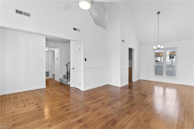 interior space featuring hardwood / wood-style flooring, ceiling fan with notable chandelier, and high vaulted ceiling