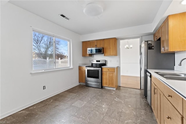 kitchen with a notable chandelier, sink, and stainless steel appliances