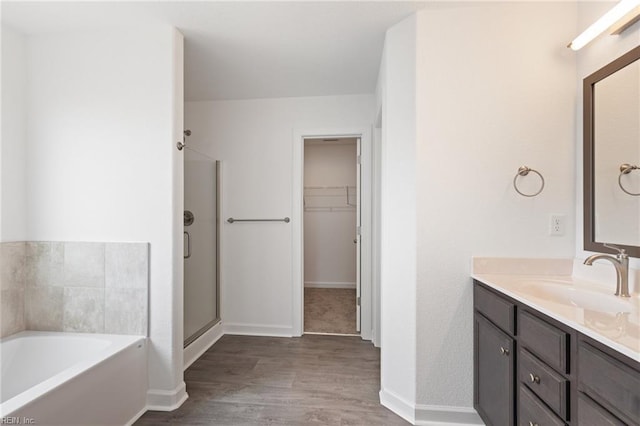 bathroom featuring plus walk in shower, vanity, and hardwood / wood-style flooring