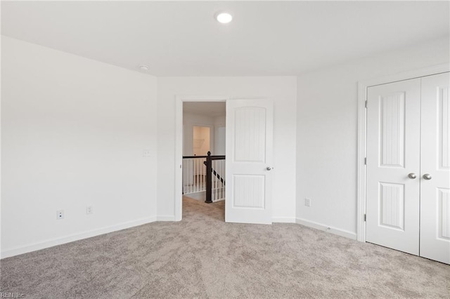 unfurnished bedroom featuring light carpet and a closet