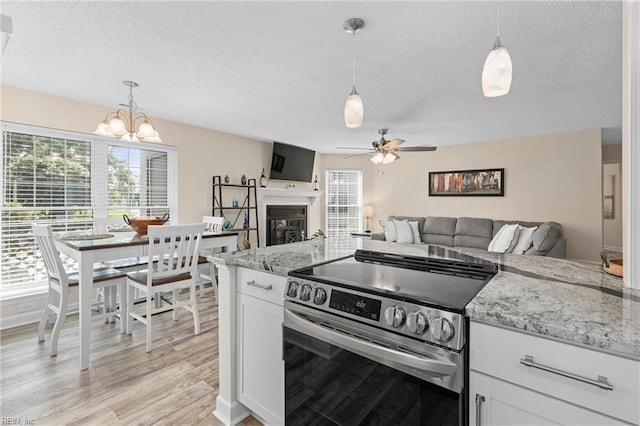 kitchen featuring white cabinets, light stone countertops, stainless steel electric range oven, and hanging light fixtures