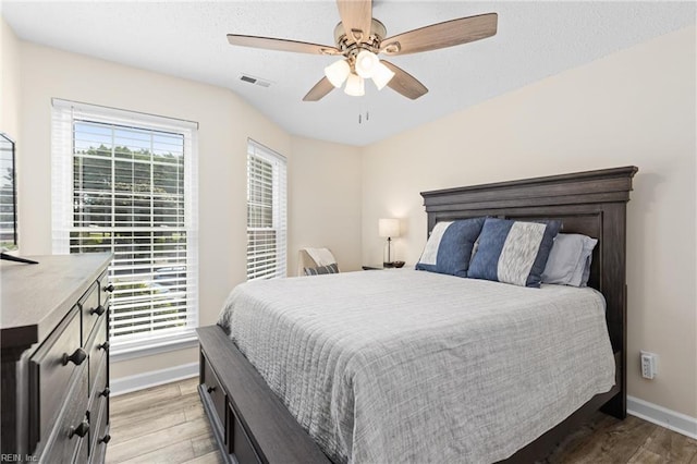 bedroom featuring multiple windows, ceiling fan, and hardwood / wood-style floors