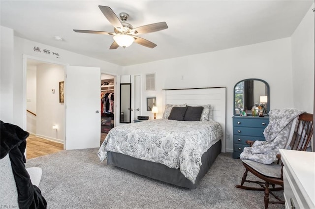 carpeted bedroom featuring ceiling fan, a spacious closet, and a closet