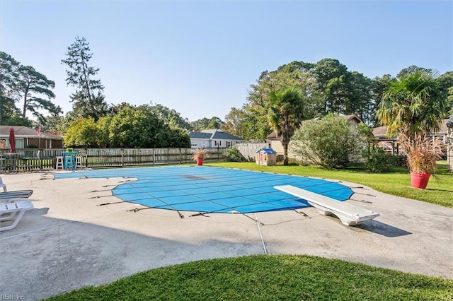 view of pool featuring a diving board, a patio area, and a lawn