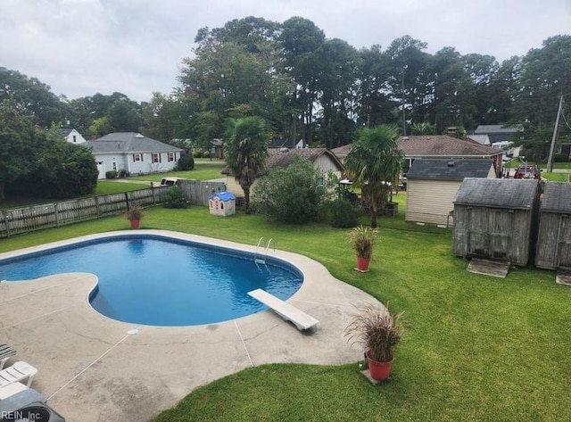 view of pool with a diving board, a shed, a yard, and a patio area