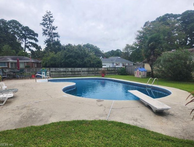 view of pool with a lawn, a diving board, and a patio