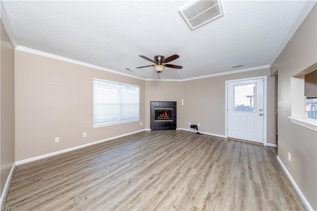 unfurnished living room featuring a fireplace, light hardwood / wood-style flooring, a textured ceiling, and ornamental molding