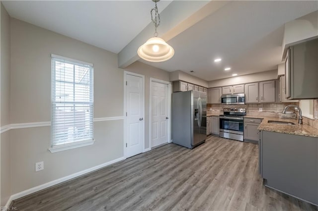 kitchen featuring tasteful backsplash, stainless steel appliances, sink, decorative light fixtures, and gray cabinets