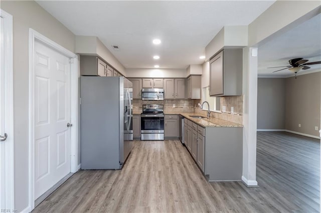 kitchen featuring ceiling fan, sink, stainless steel appliances, light stone counters, and gray cabinets