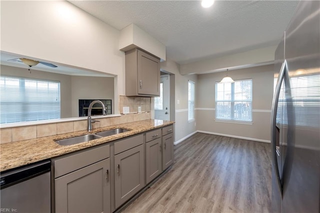 kitchen featuring gray cabinetry, sink, appliances with stainless steel finishes, tasteful backsplash, and light hardwood / wood-style floors