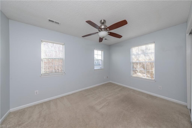 unfurnished room with a textured ceiling, ceiling fan, and light carpet